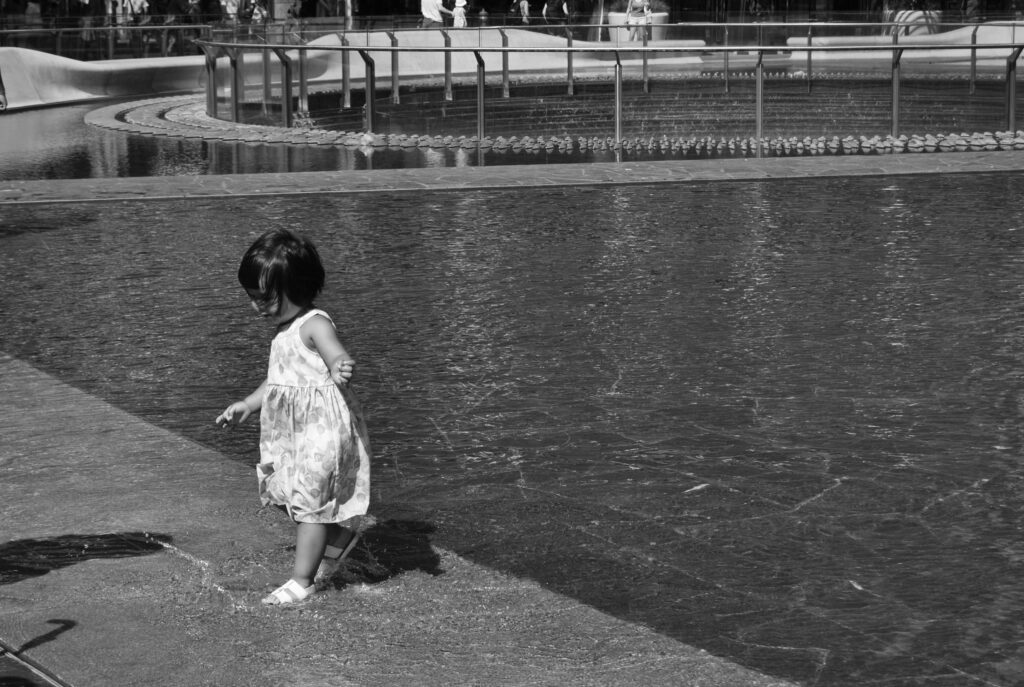 street photography black and white little girl in the water playing