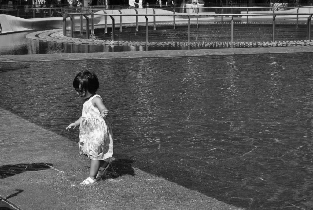 street photography black and white little girl in the water playing